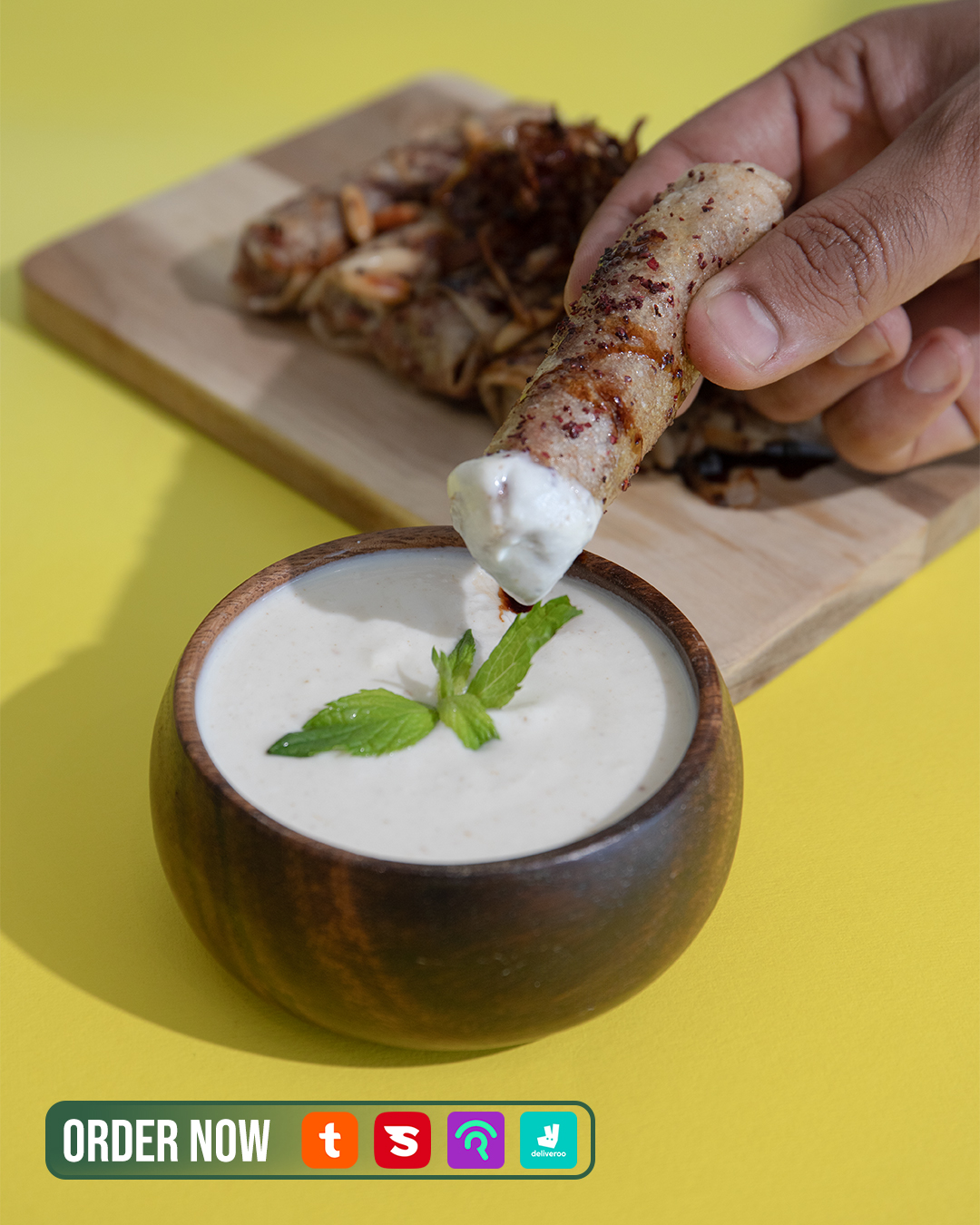 Tawlet Beirut roll dipped in sauce on a yellow background